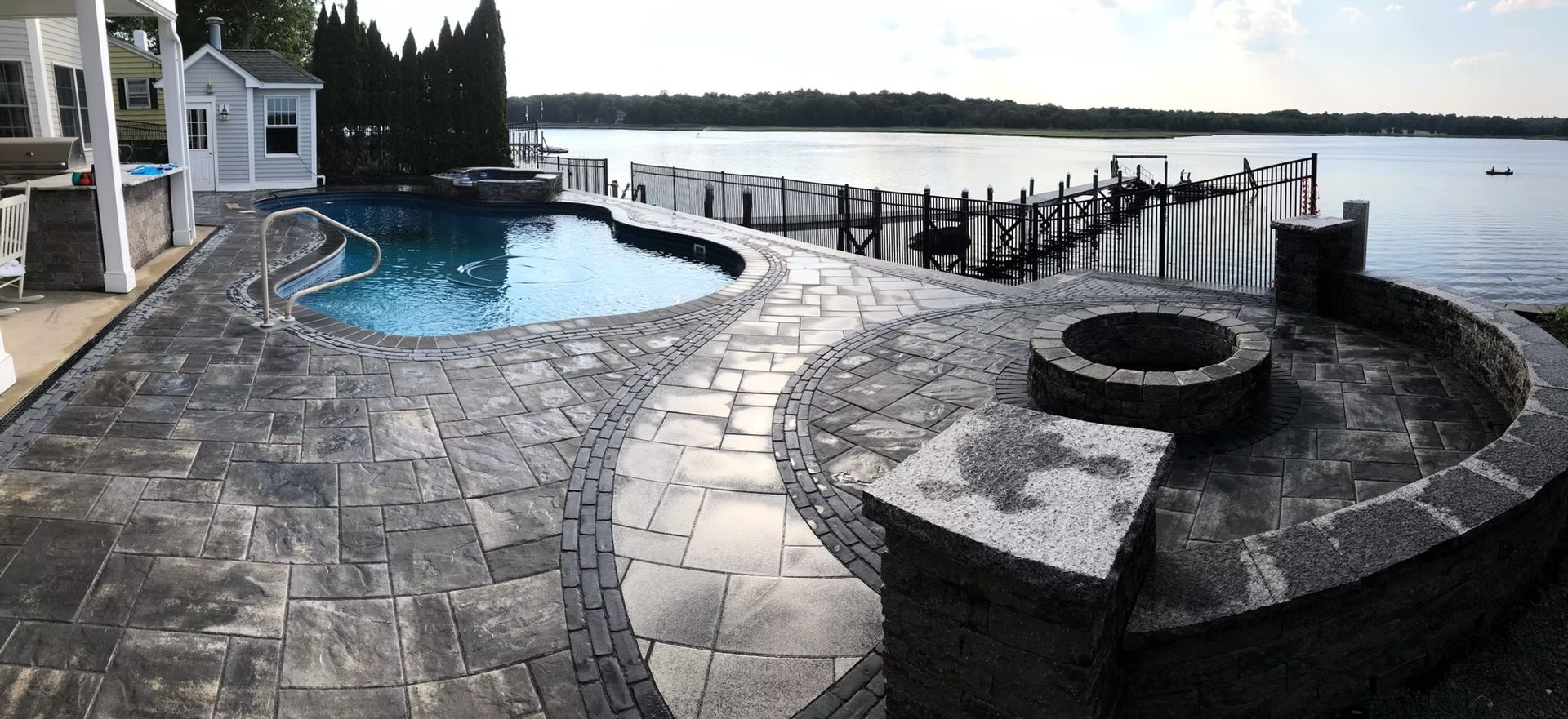 Backyard patio with pool, fire pit, and lake view.