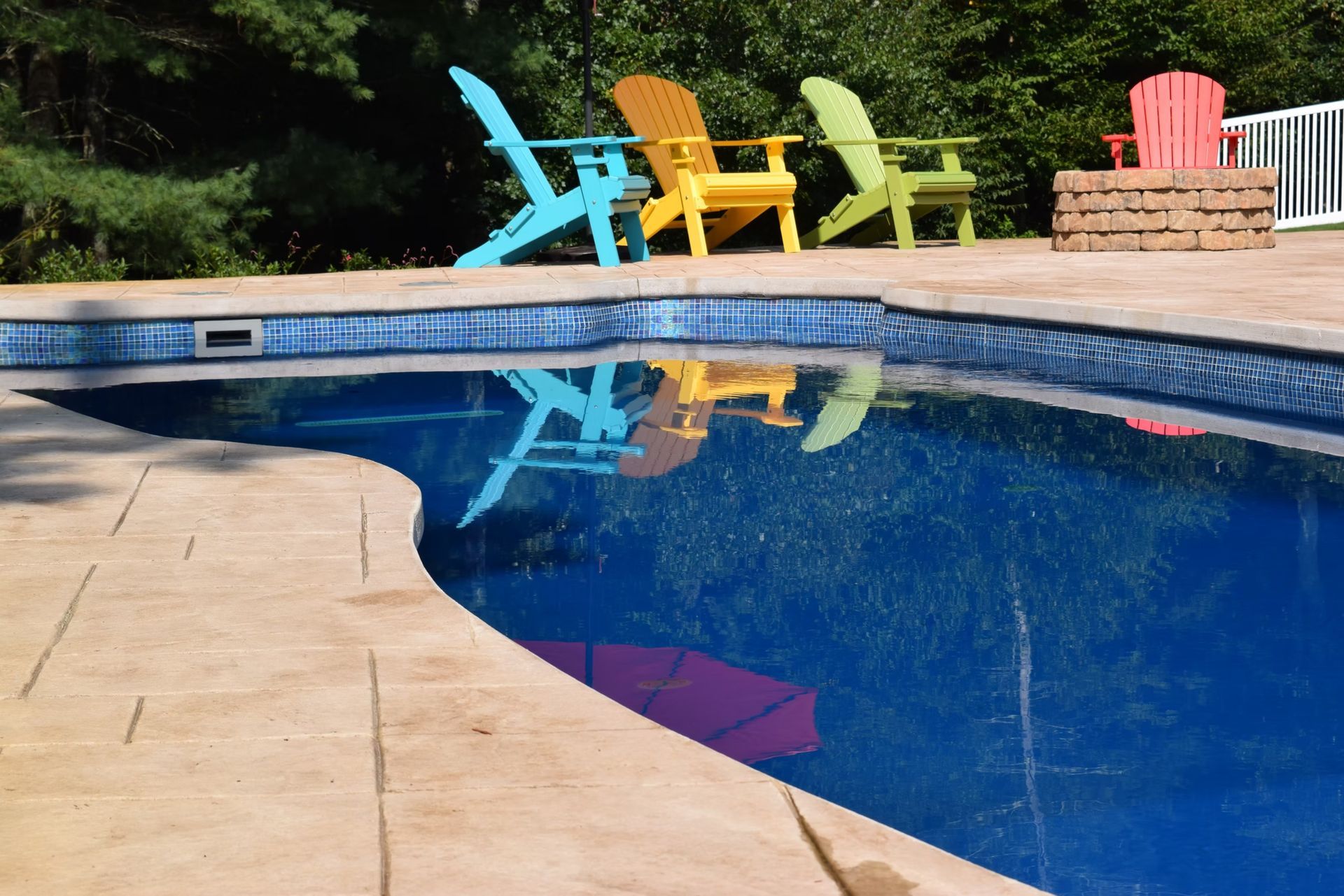 Pool with colorful Adirondack chairs reflecting in the water.