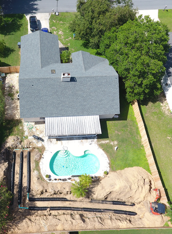 Aerial view of a house with a pool and construction in the backyard.