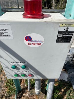 Control box with lights and buttons, featuring an All-in-One Septic sticker and a red emergency light on top.