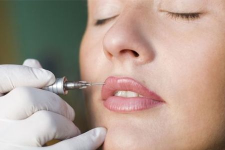 A woman is getting a permanent makeup tattoo on her lips.