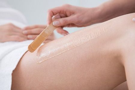 A woman is getting a waxing treatment on her leg.