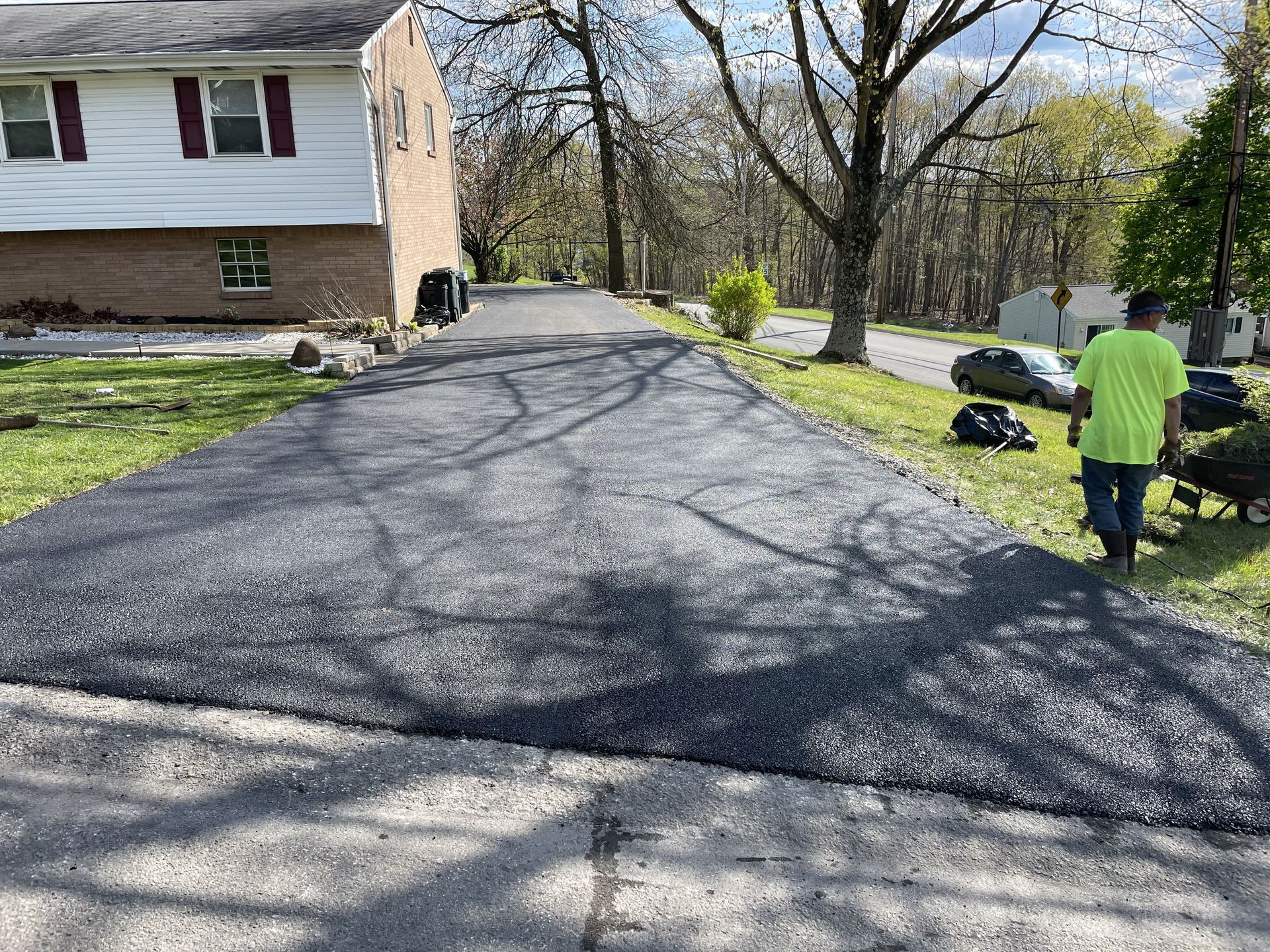 A freshly paved asphalt driveway with a worker in a neon green shirt.