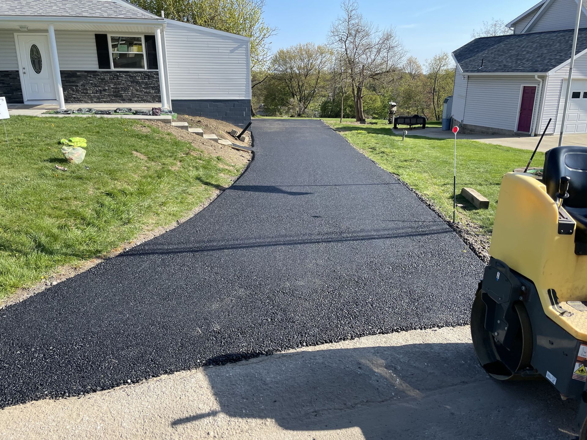 New asphalt driveway being paved in front of a house.