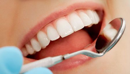 A woman is getting her teeth examined by a dentist.
