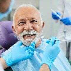 A man with a beard is getting his teeth examined by a dentist.