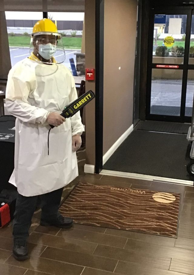 a man in a lab coat and hard hat is holding a metal detector .