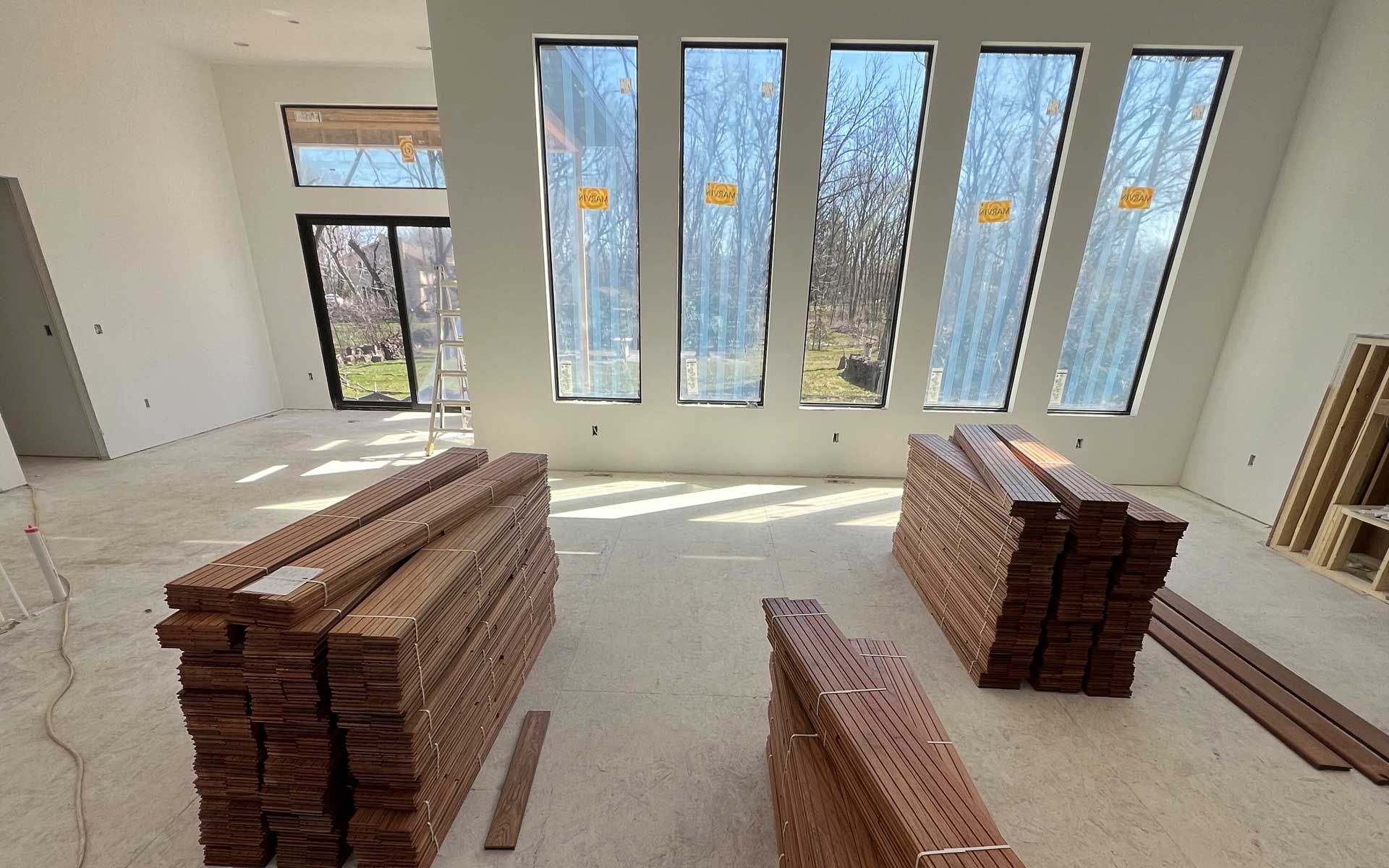 A room with a lot of windows and stacks of wood on the floor.