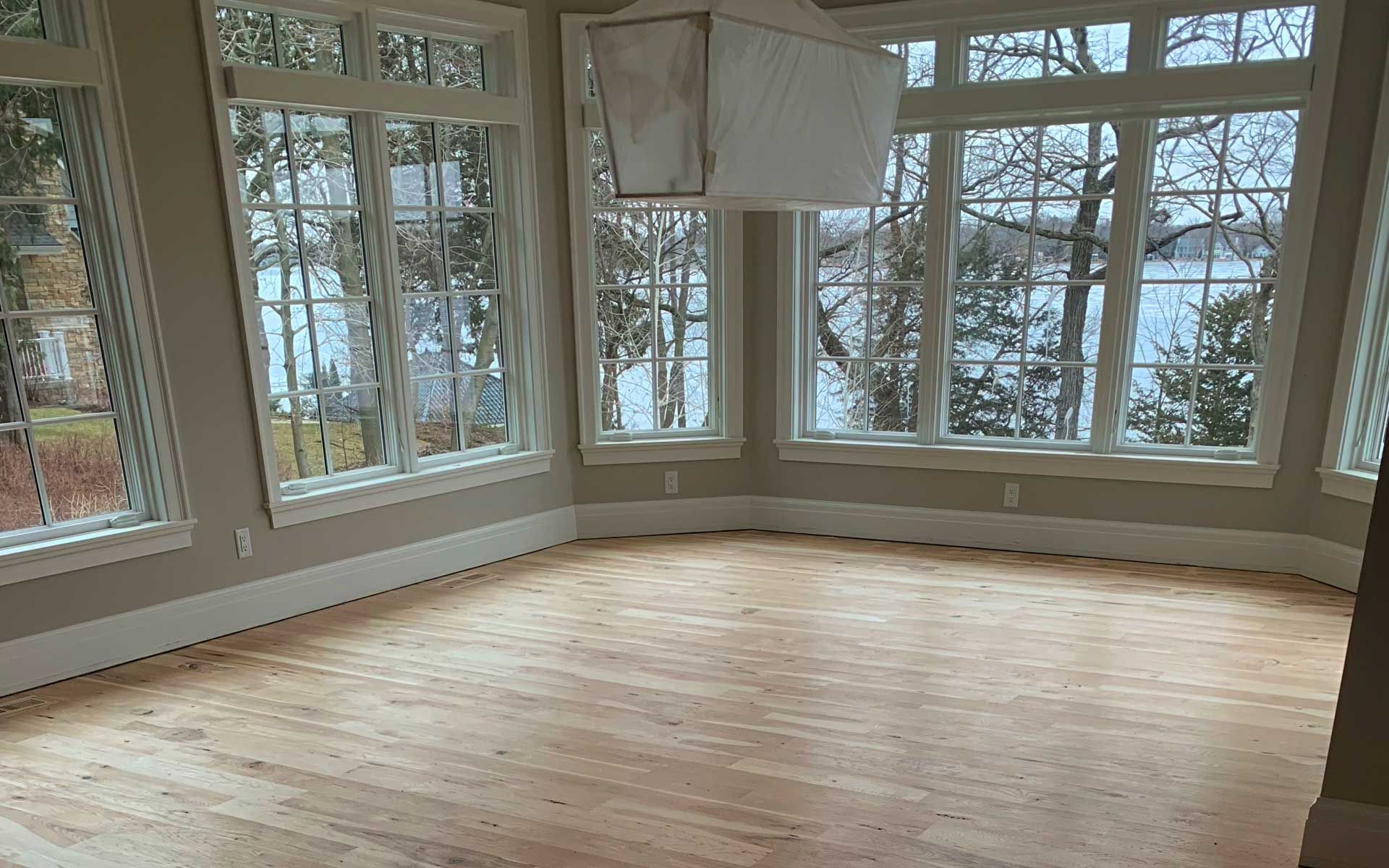 An empty room with a lot of windows and a wooden floor.