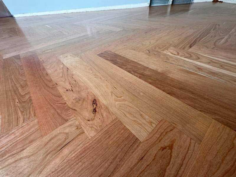 A close up of a wooden floor with a herringbone pattern.