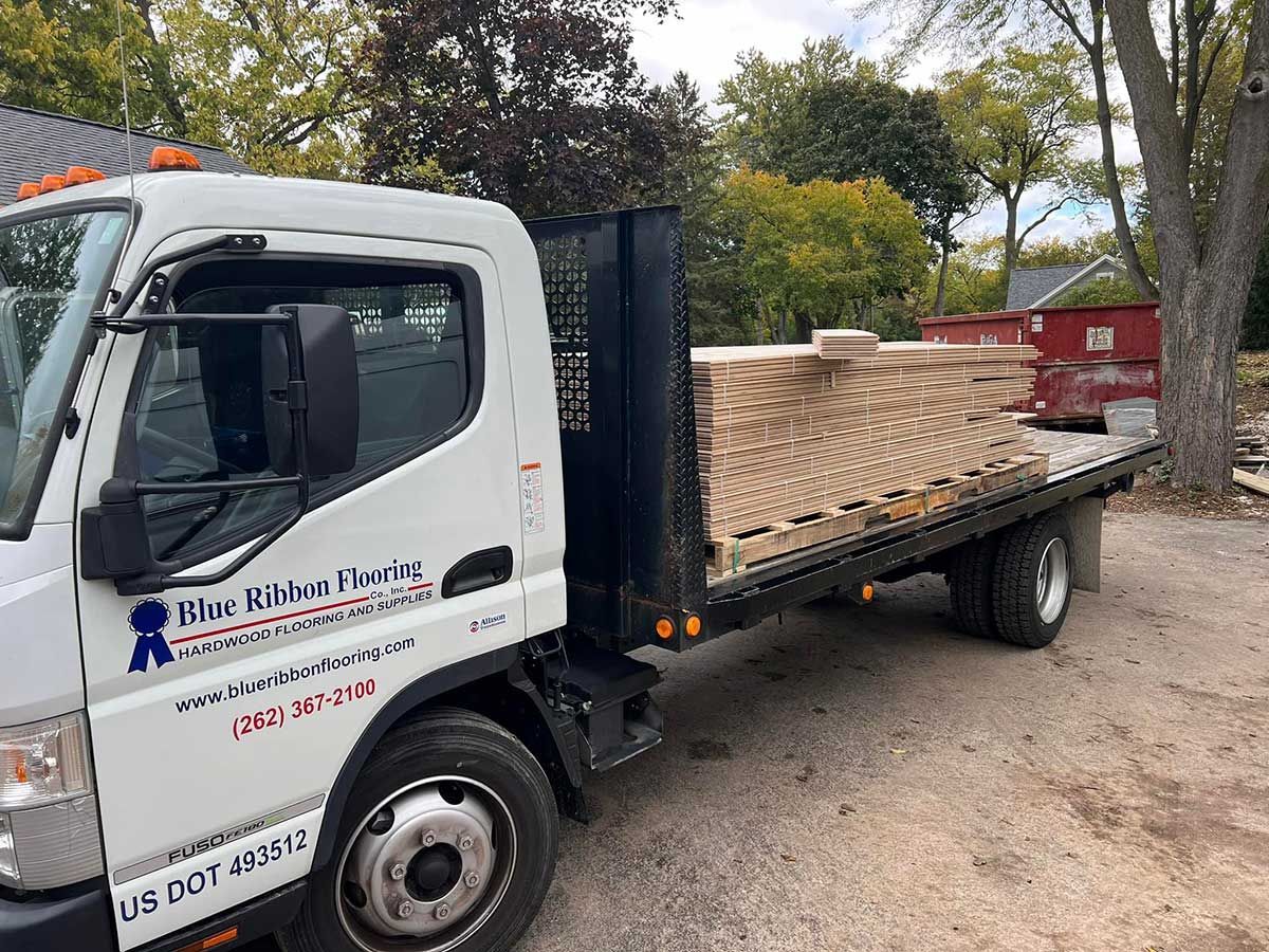 A tow truck with a flatbed is parked in a parking lot.