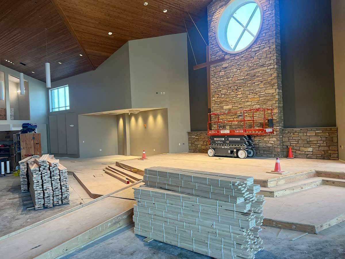 A large room with a stone fireplace and a stack of bricks on the floor.
