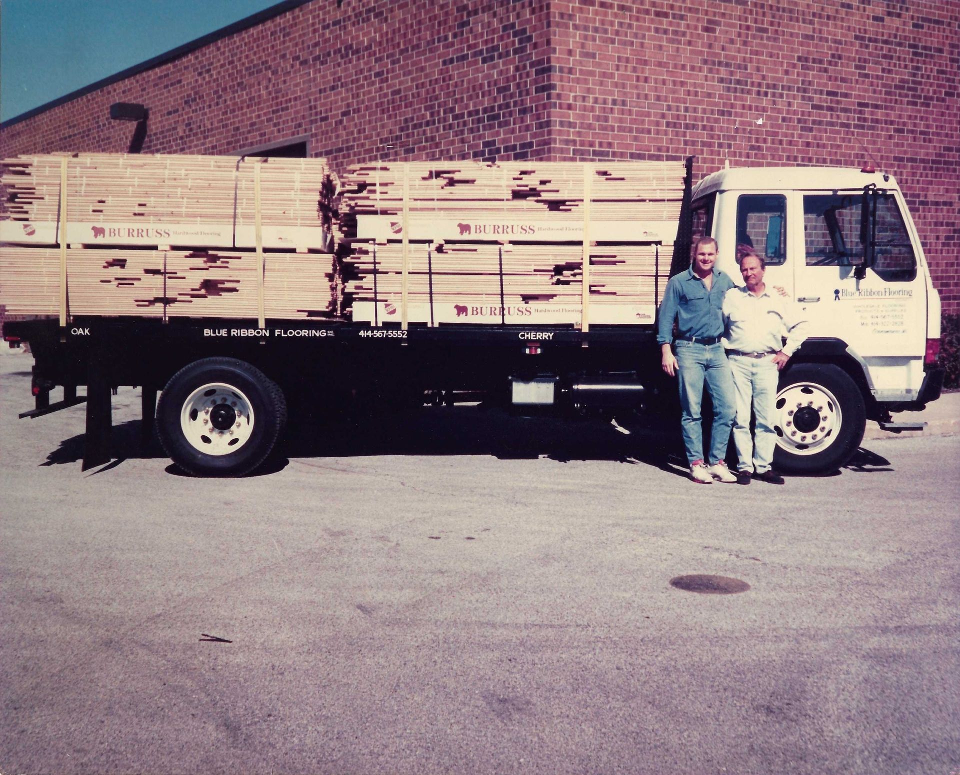 Two men standing in front of a truck that says ' williams ' on the side