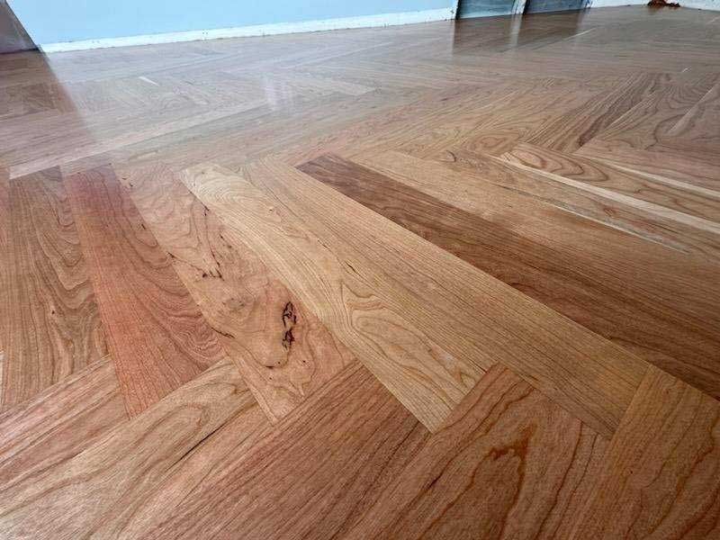 A close up of a wooden floor with a herringbone pattern.