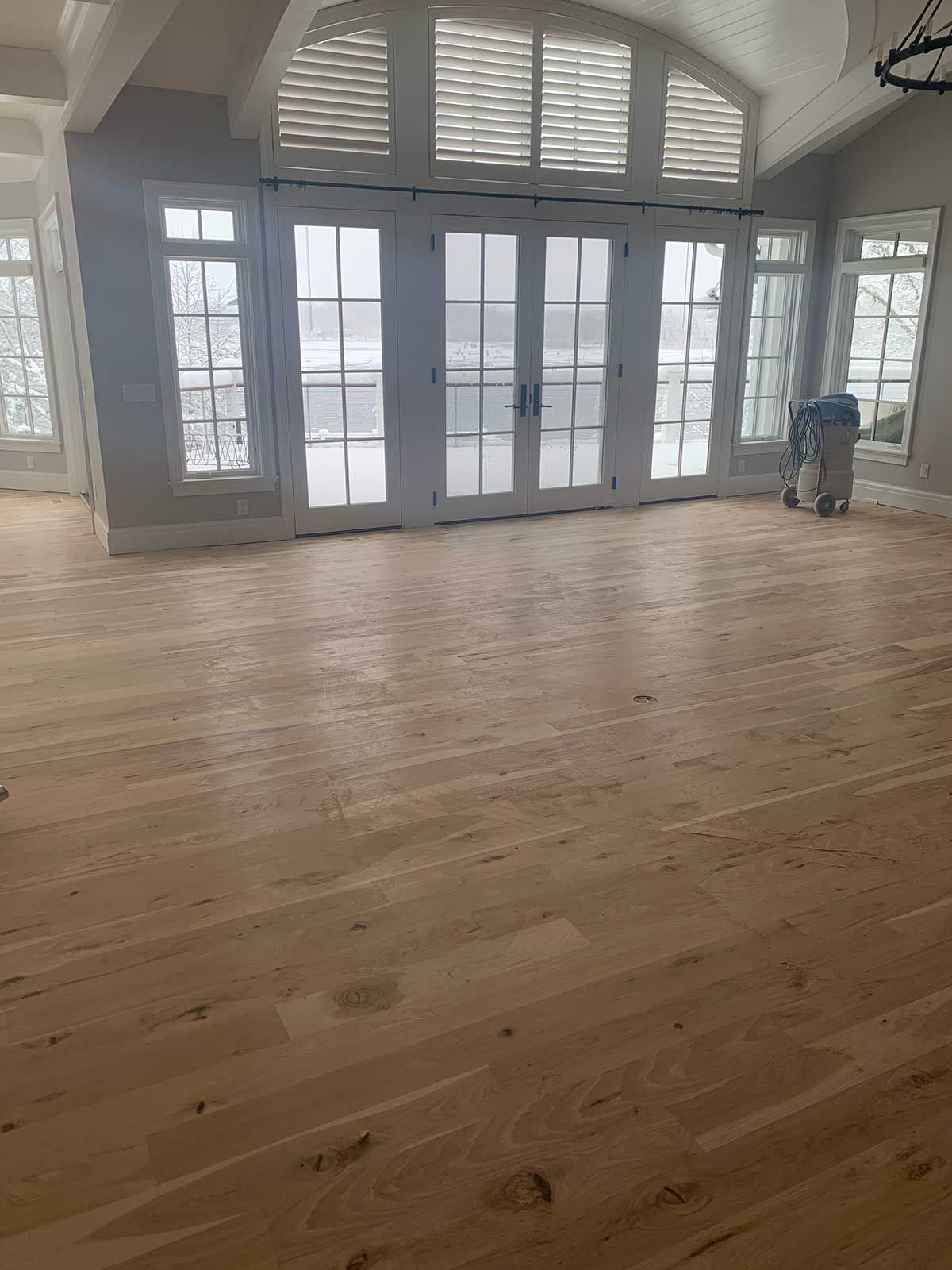 A large empty room with hardwood floors and lots of windows.