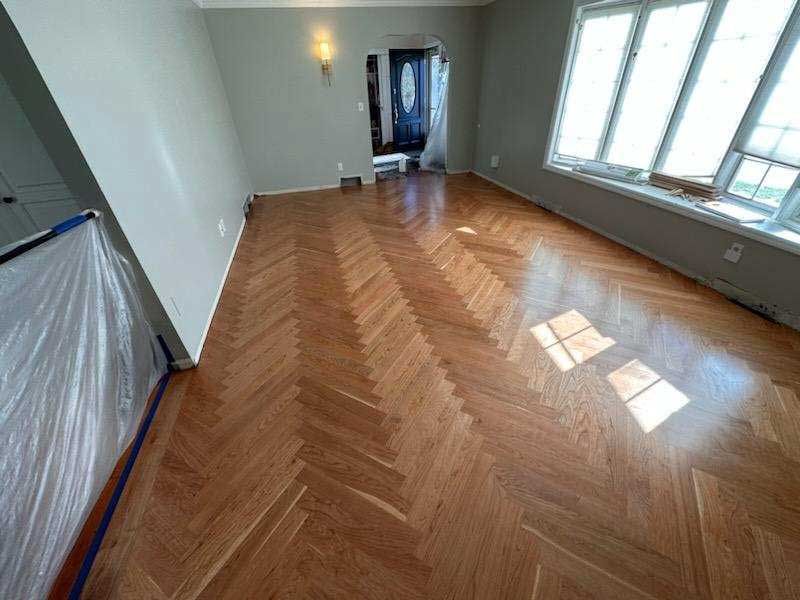 A living room with a wooden floor and a herringbone pattern.