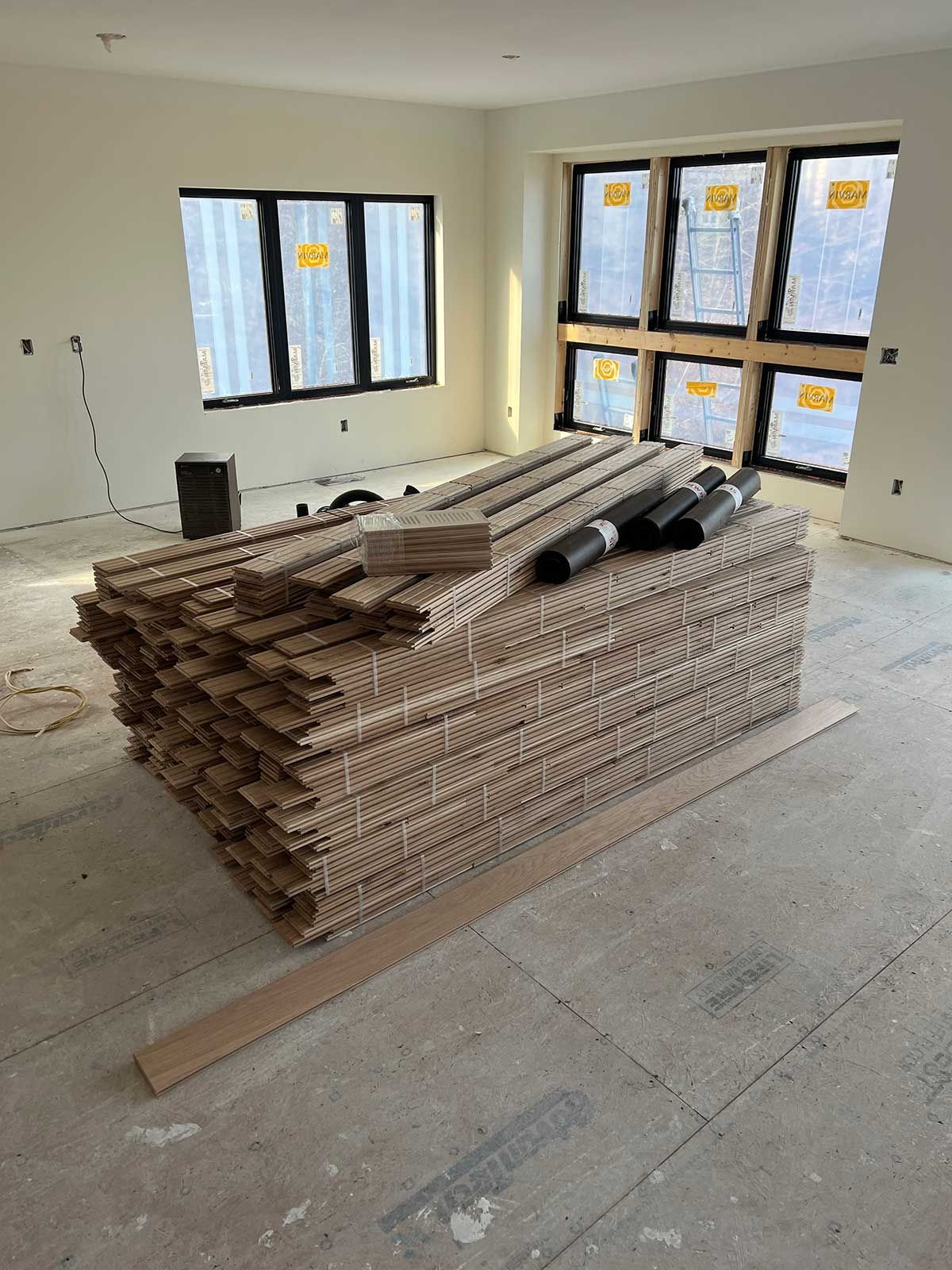 A stack of wooden boards is sitting on the floor in a room under construction.