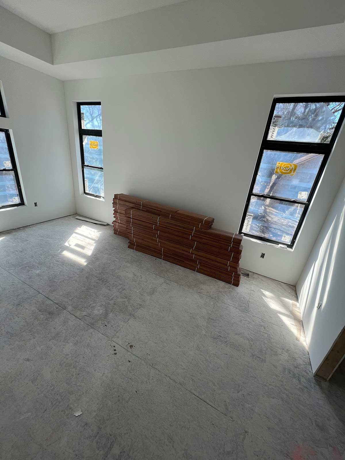 A room with a lot of windows and a wooden shelf on the floor.