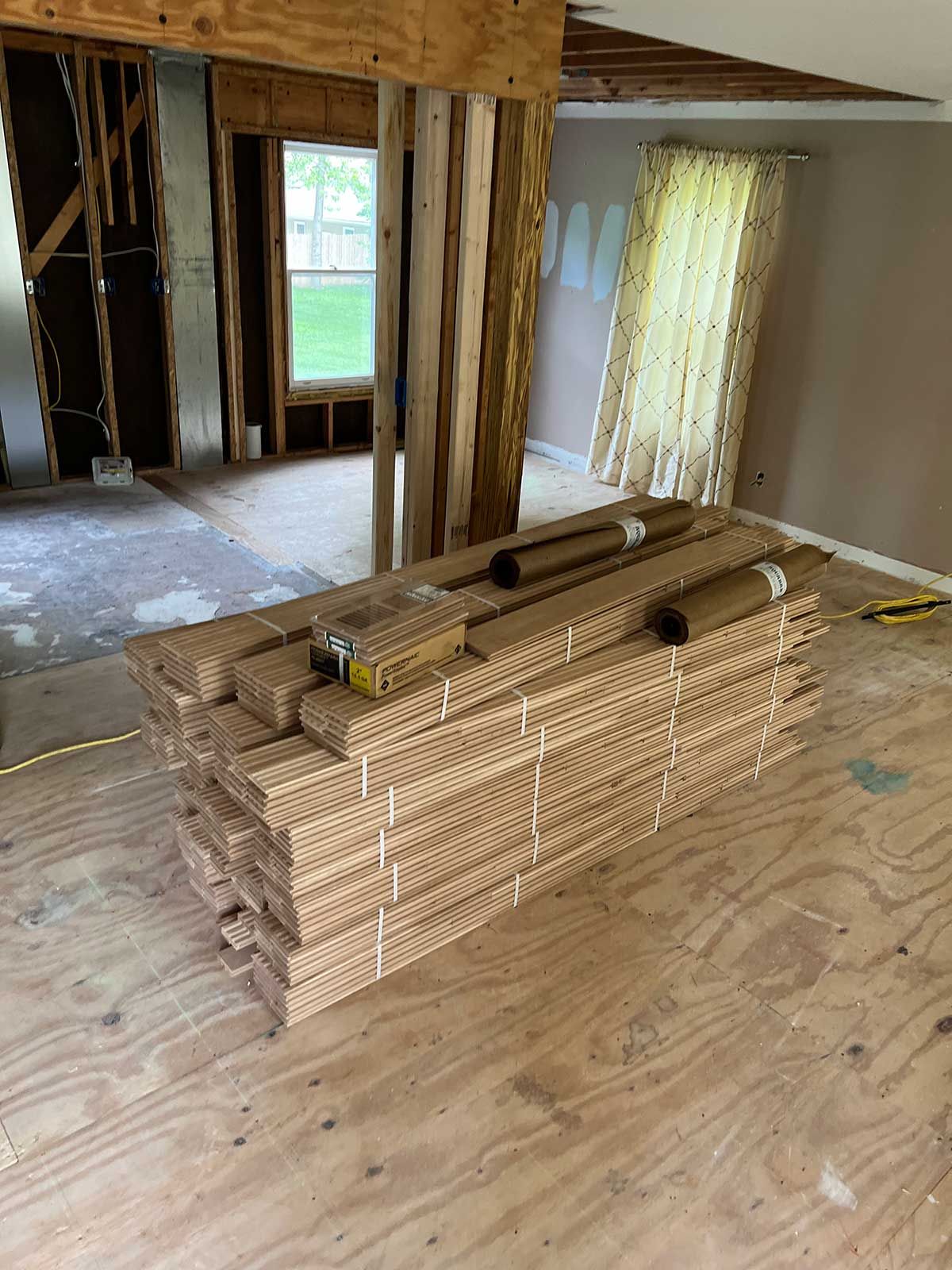 A stack of wooden boards is sitting on a wooden floor in a room.