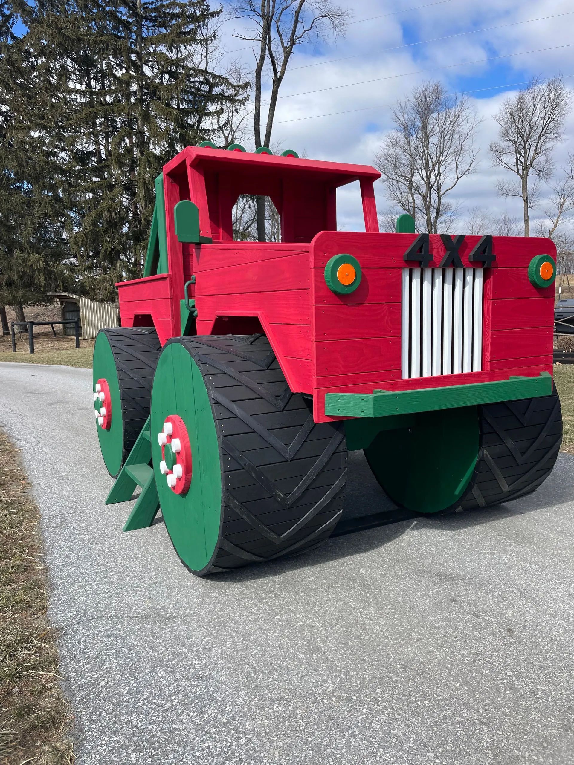 A red and green toy truck is parked on the side of a road.