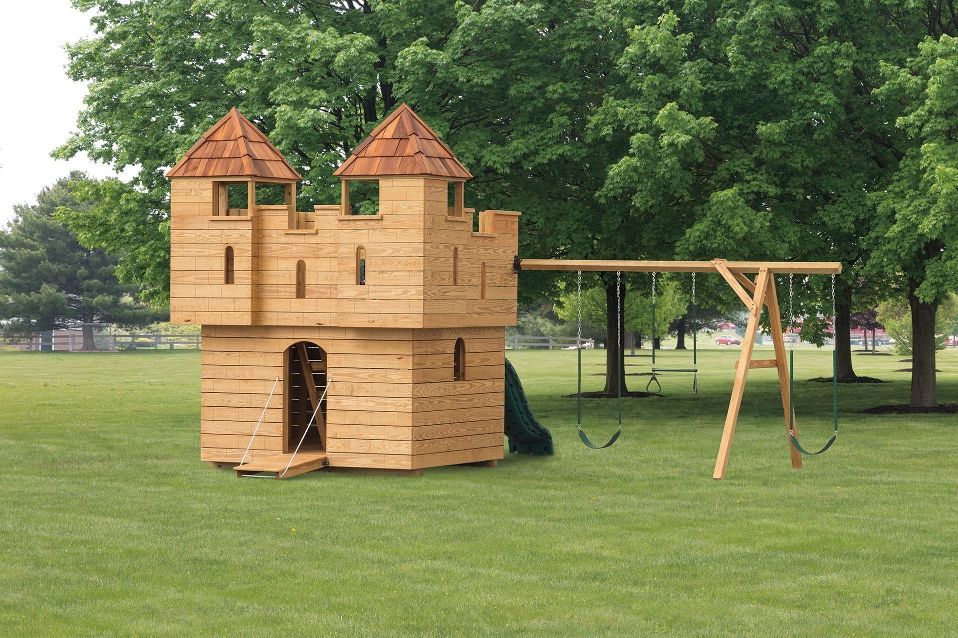 A wooden castle with swings and a slide in a park