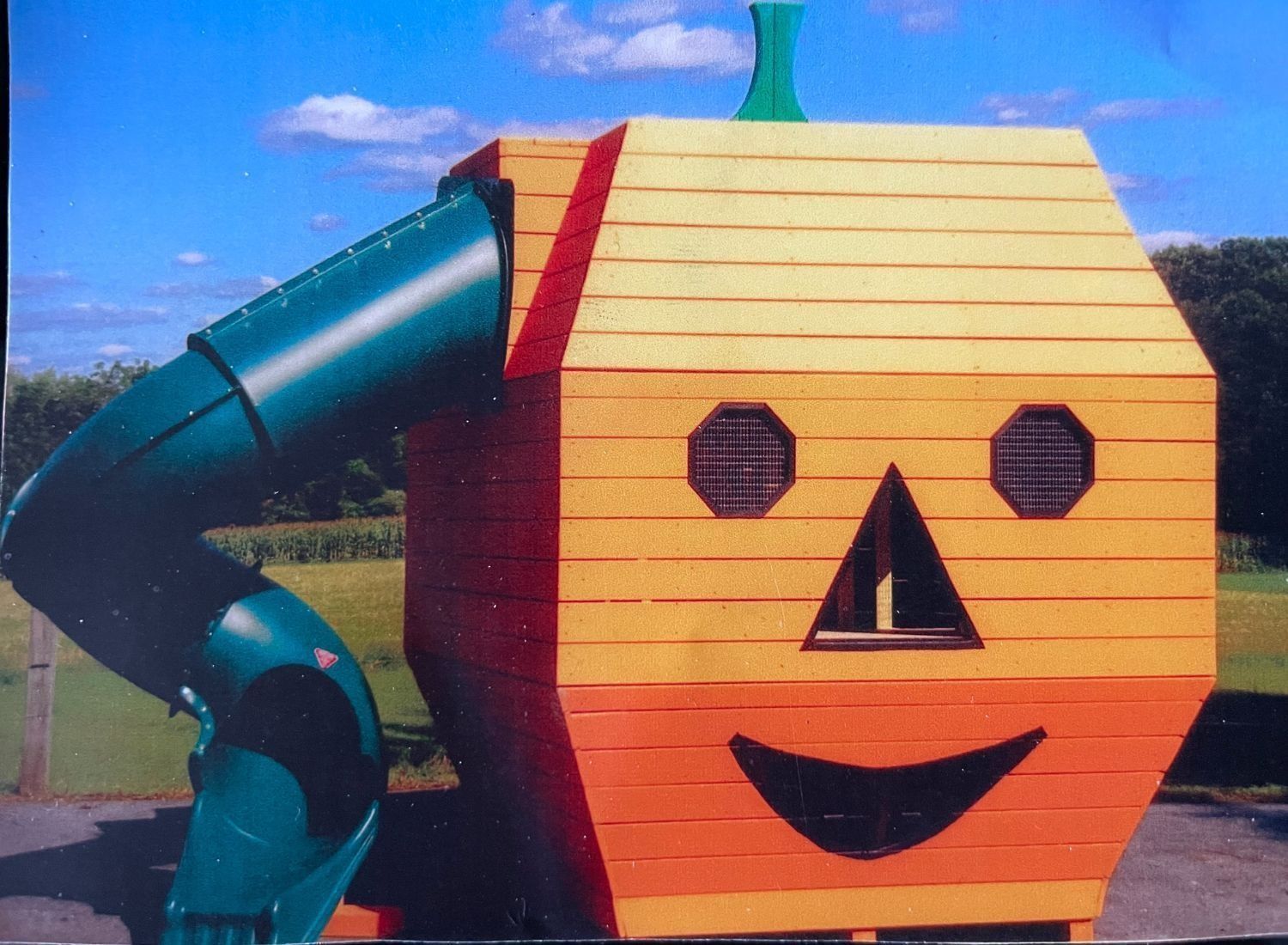 A wooden pumpkin with a green slide attached to it