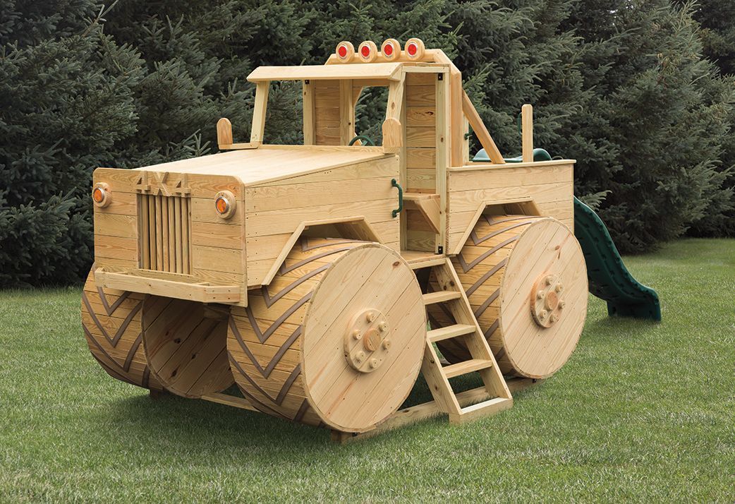 A wooden monster truck is sitting on top of a lush green field.