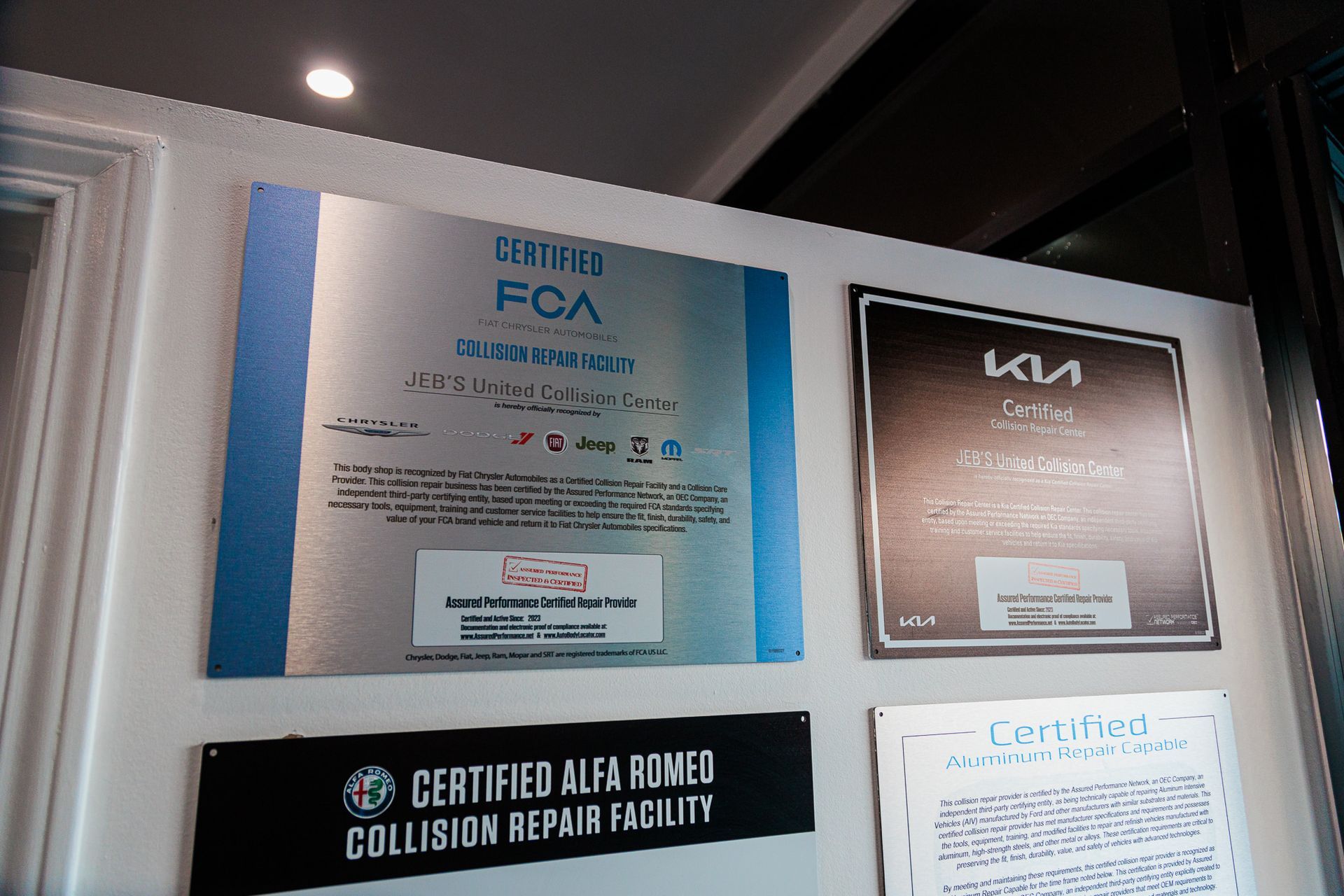 A certified alfa romeo collision repair facility sign hangs on a wall