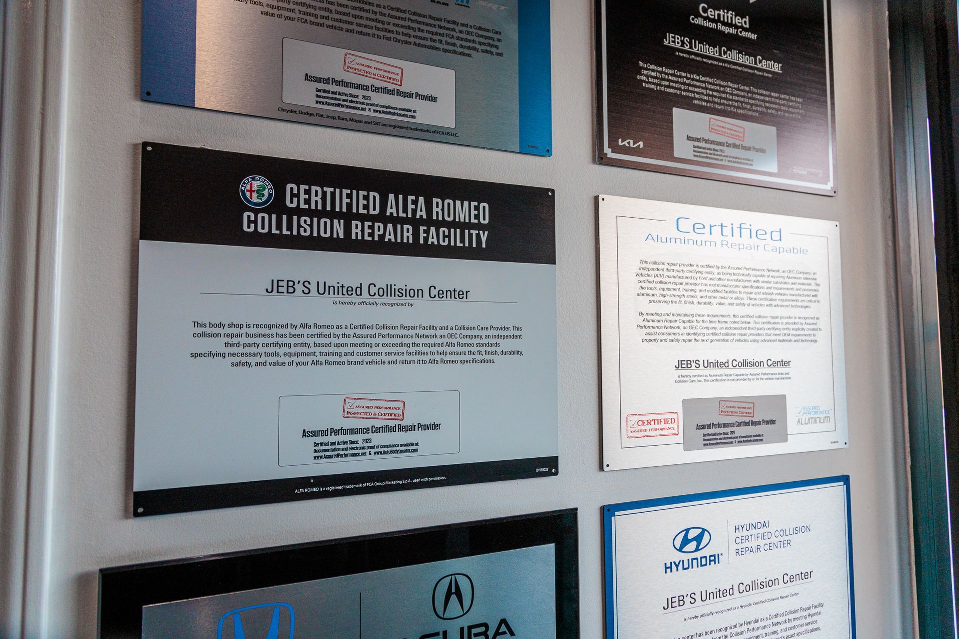 A certified collision repair facility certificate hangs on a wall