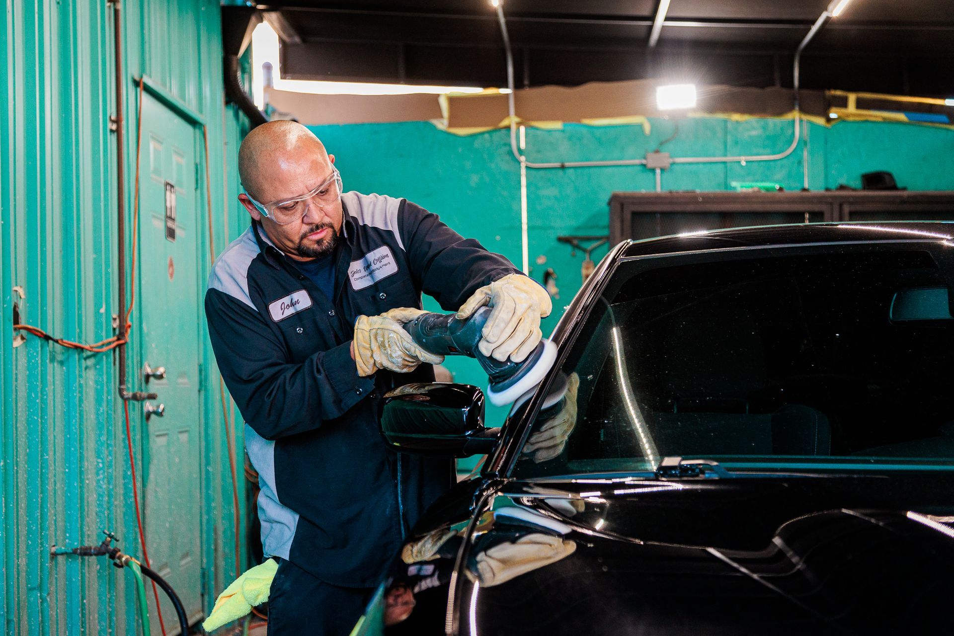 A man is polishing a car in a garage.