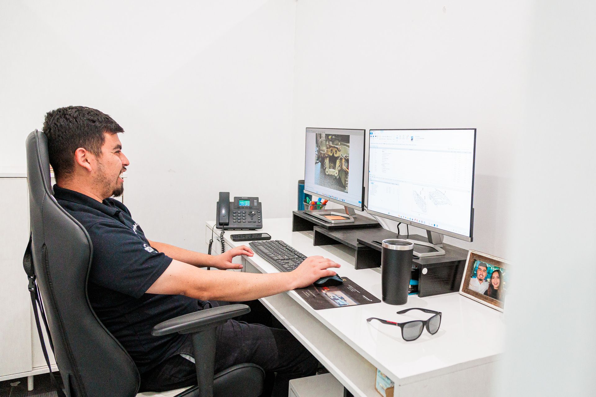 A man is sitting at a desk in front of two computer monitors.