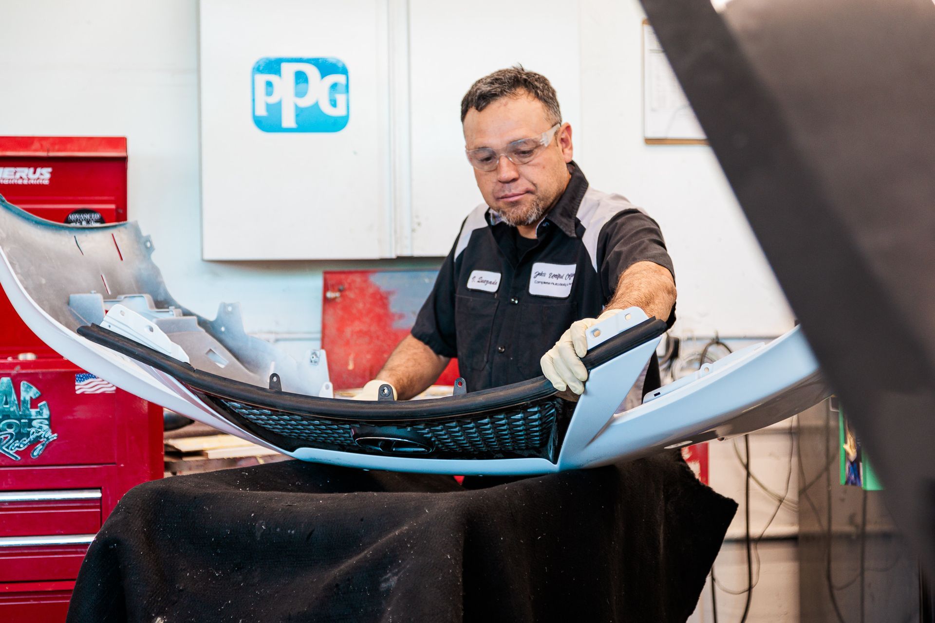 A man is working on a bumper in a garage.