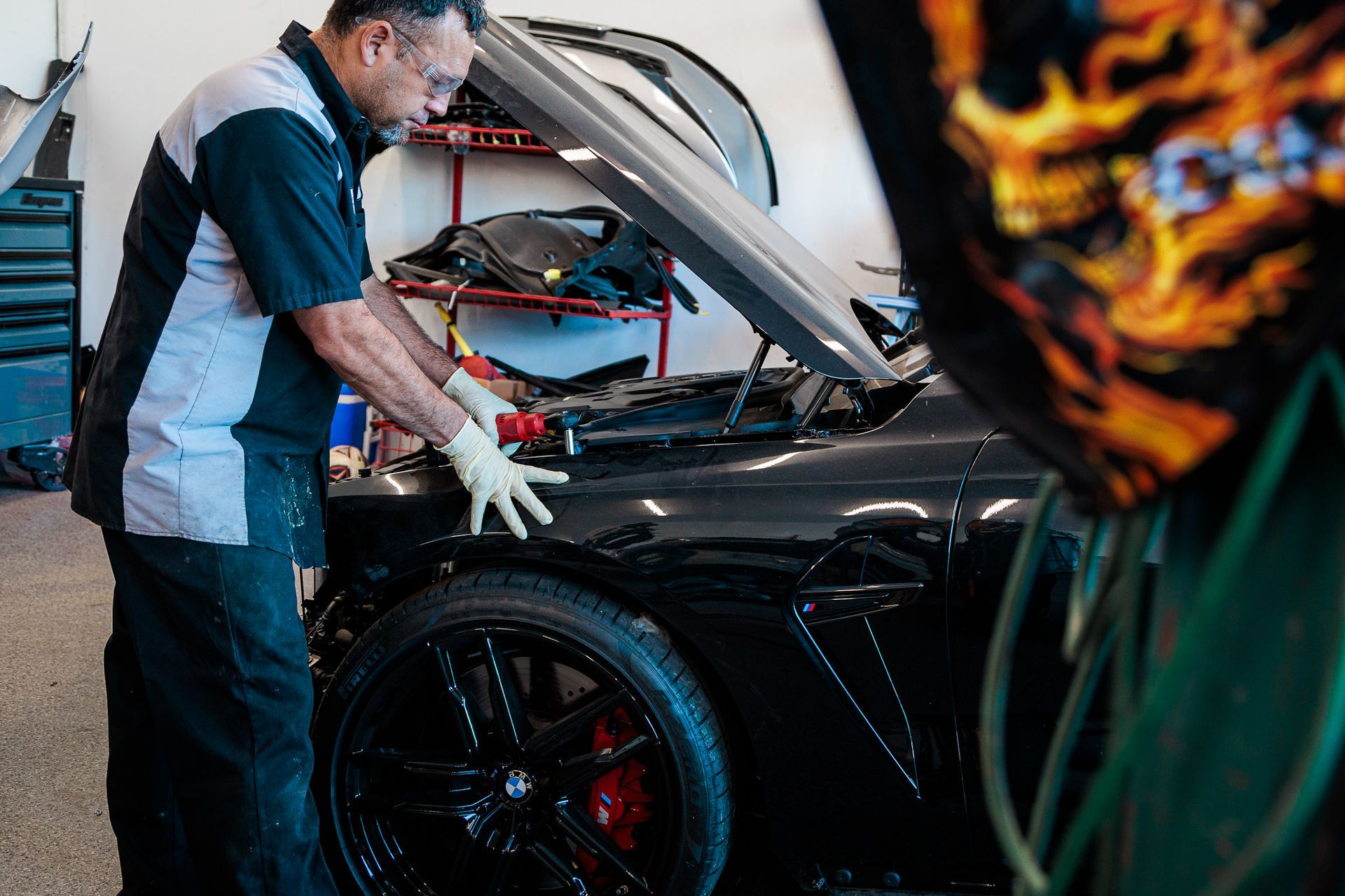 A man is working on a car with the hood up in a garage.