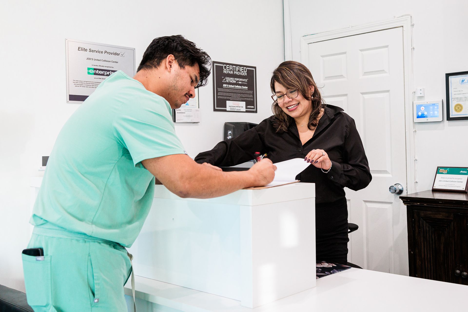 A man and a woman are standing at a counter in an  auto repair shop