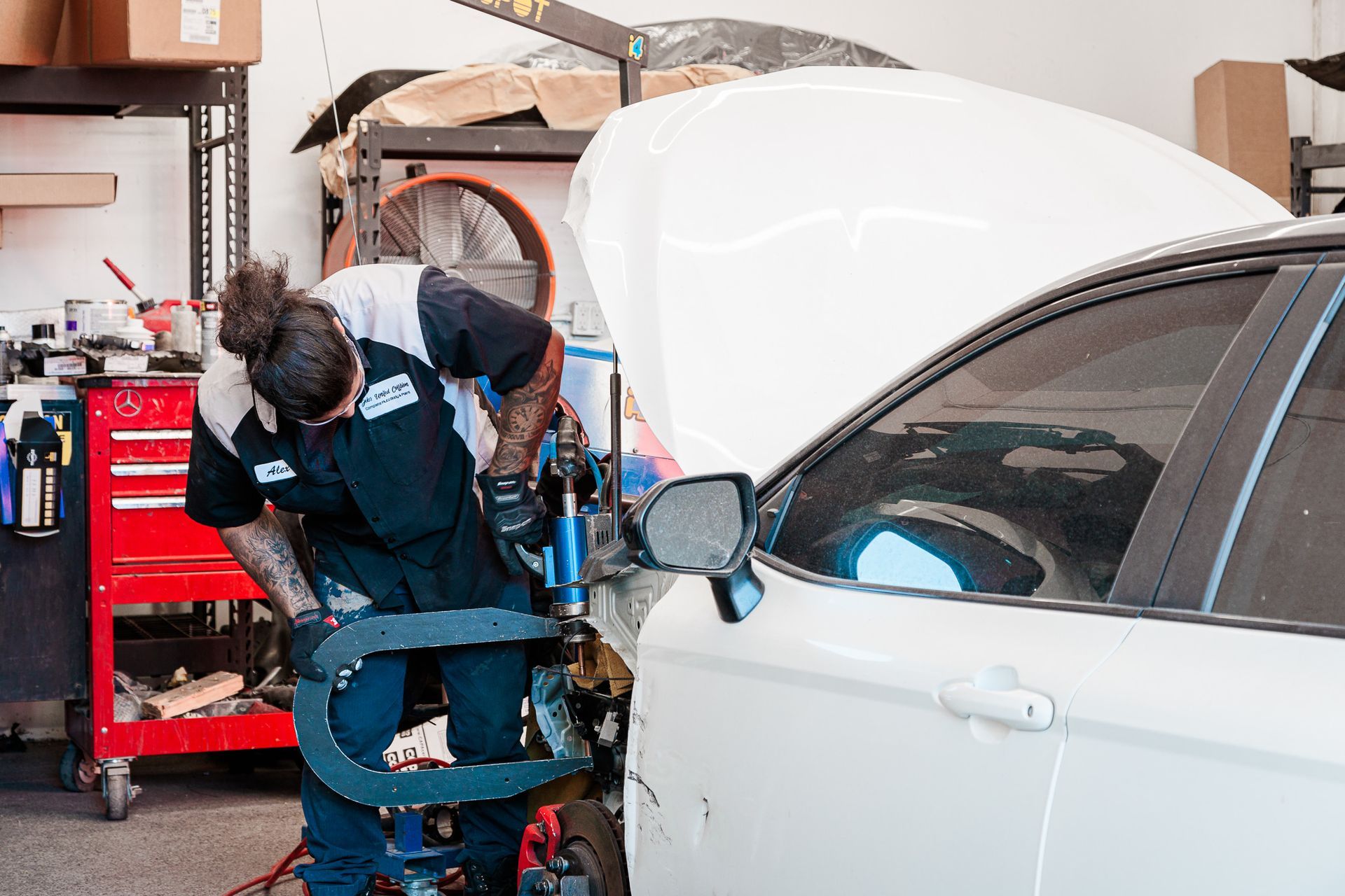 A man is working on a white car in a garage.