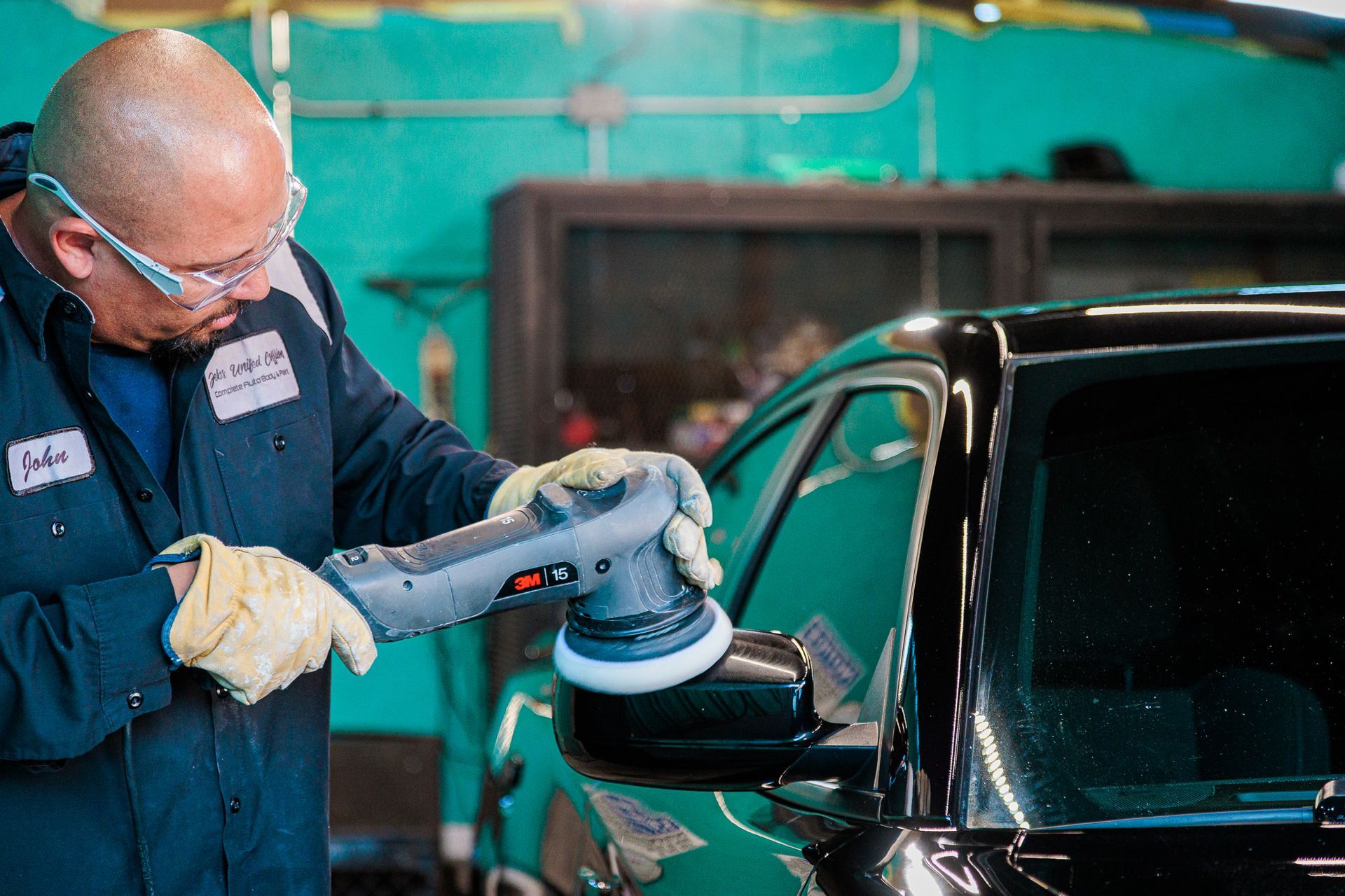 Man polishing a car with a machine in a garage.