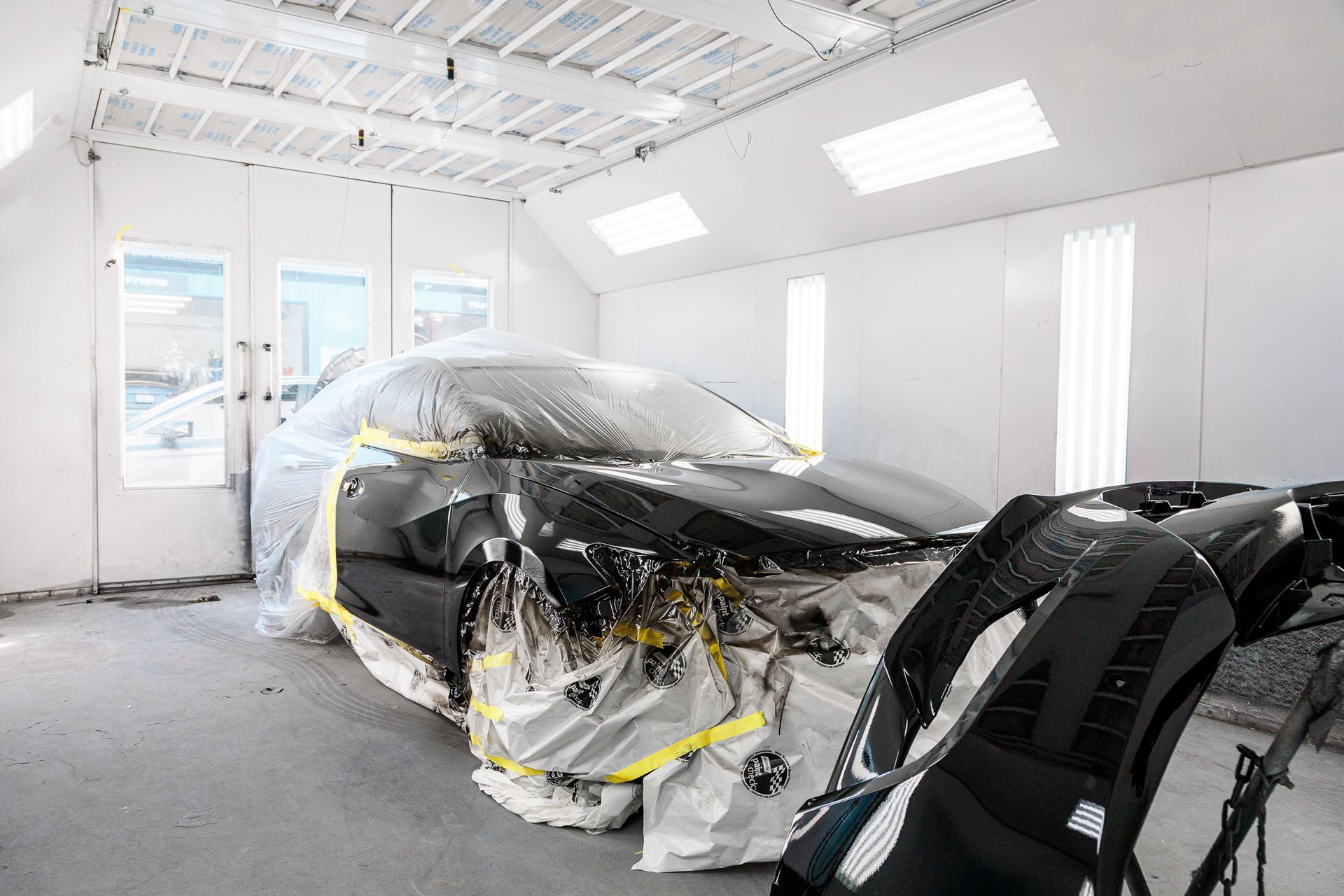 A car is being painted in a paint booth.