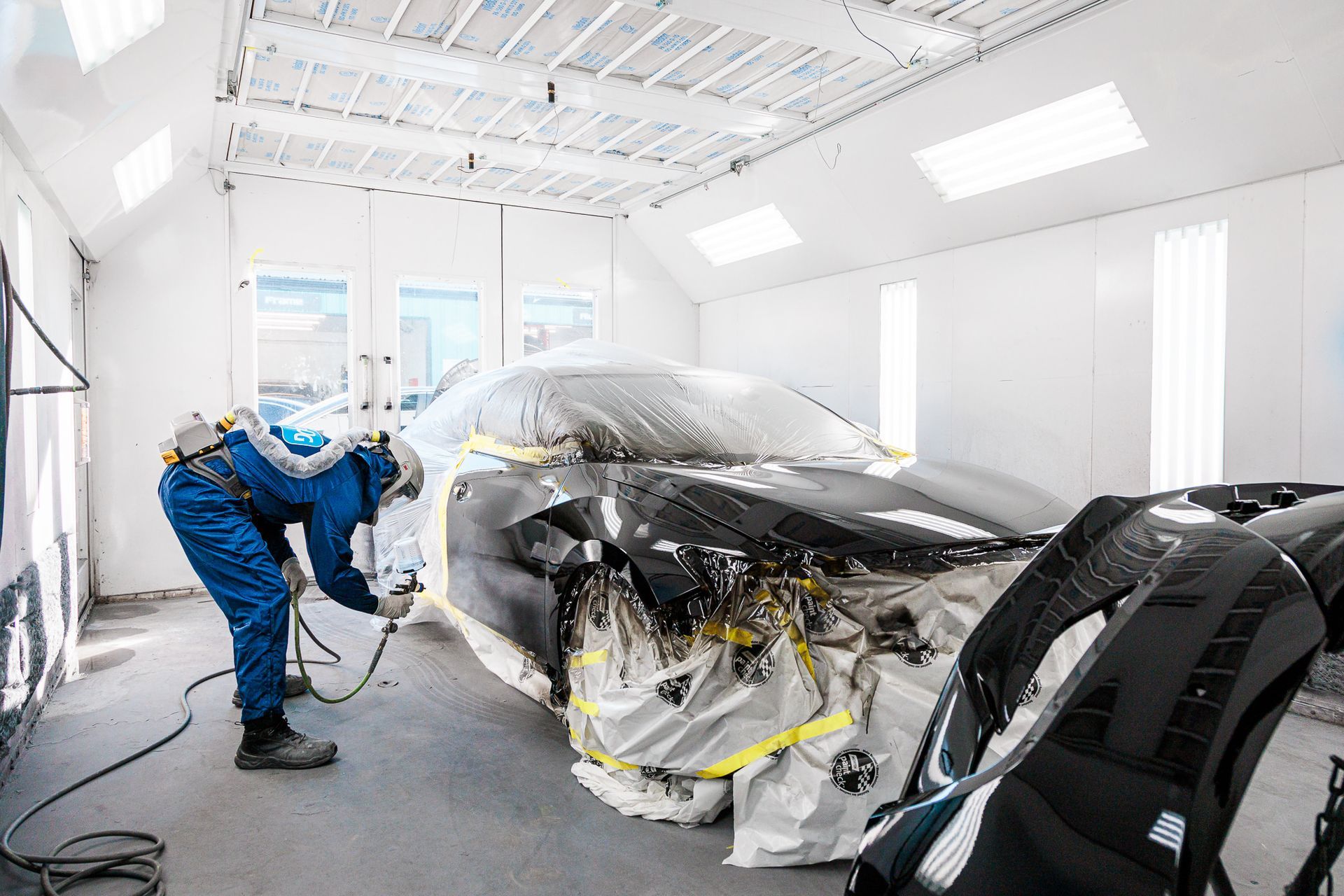 A man is painting a car in a garage.
