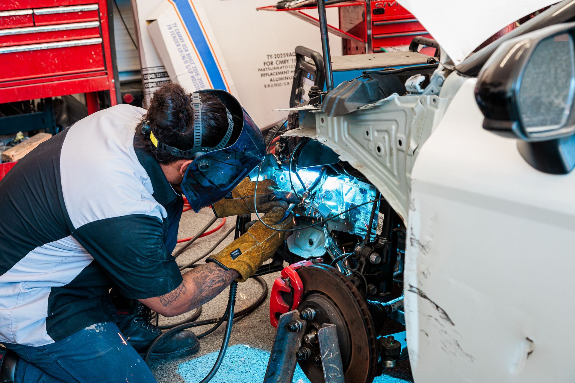 A man is welding a car in a garage.