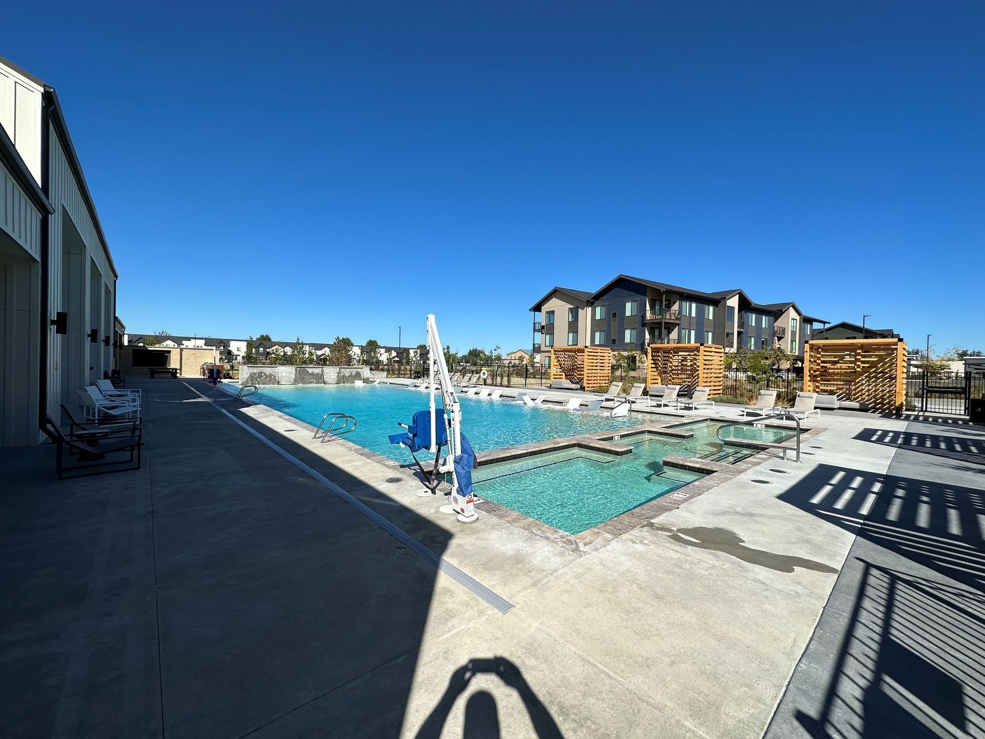 A large swimming pool is surrounded by chairs and a building.