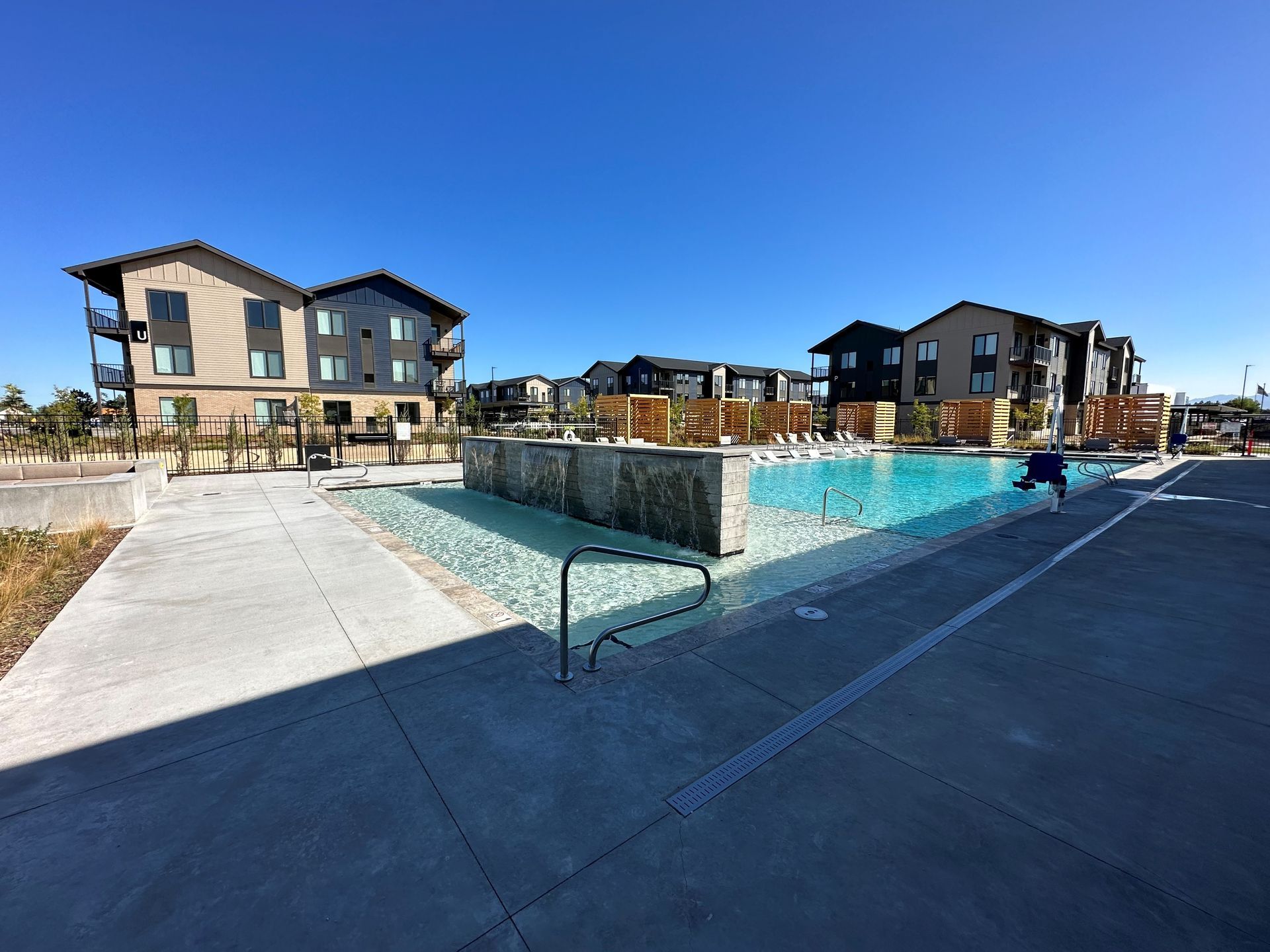 A large swimming pool in front of a large apartment building.