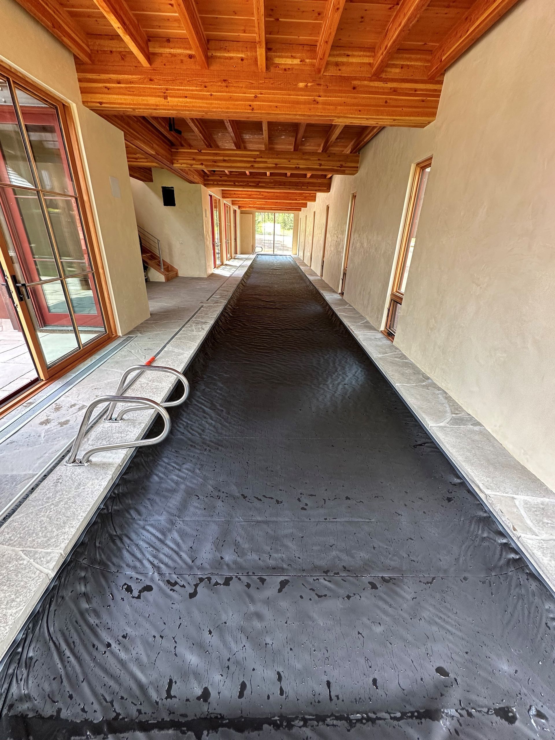 A long hallway with a concrete floor and a wooden ceiling.