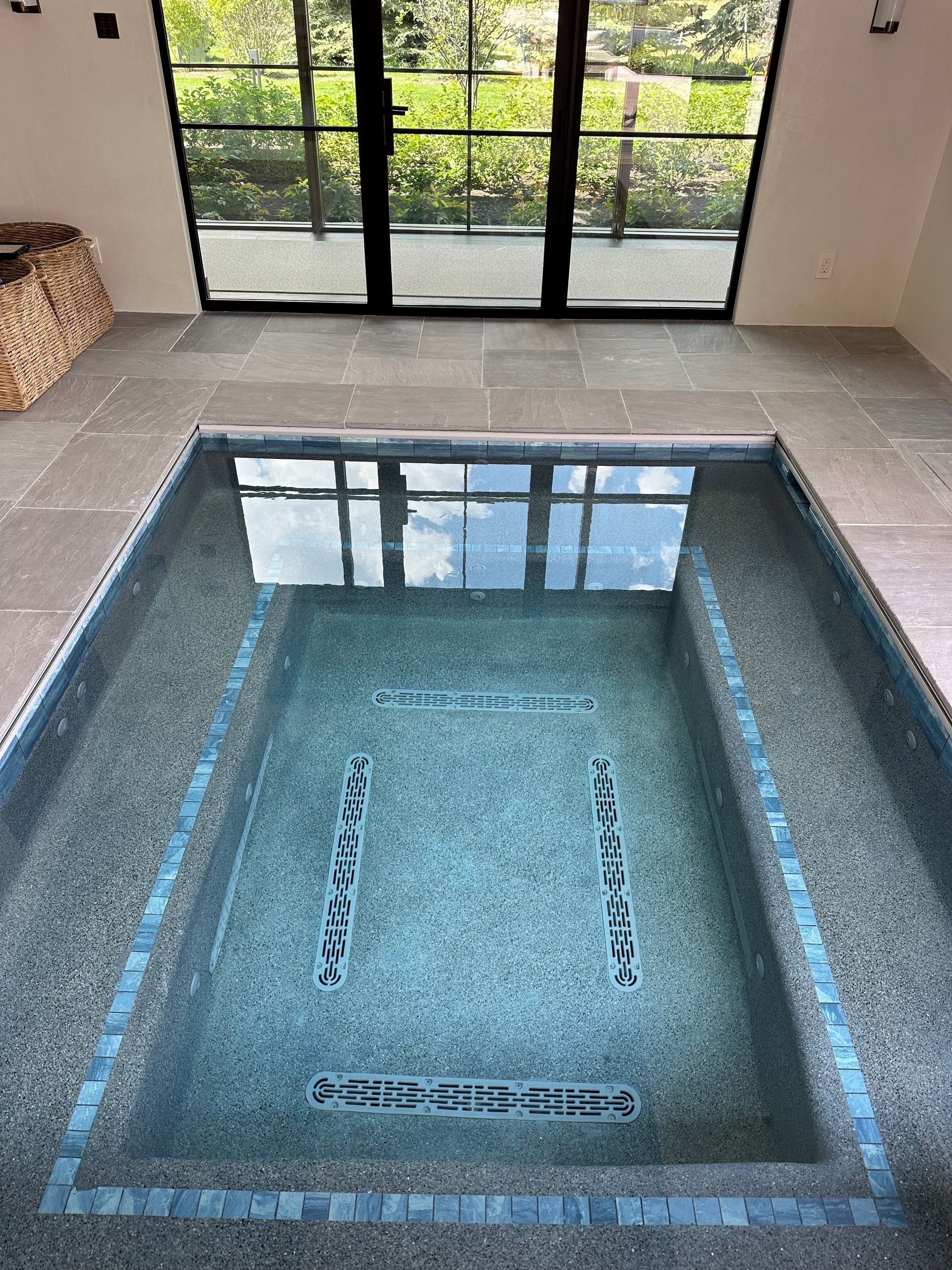 A large rectangular swimming pool in a room with sliding glass doors.