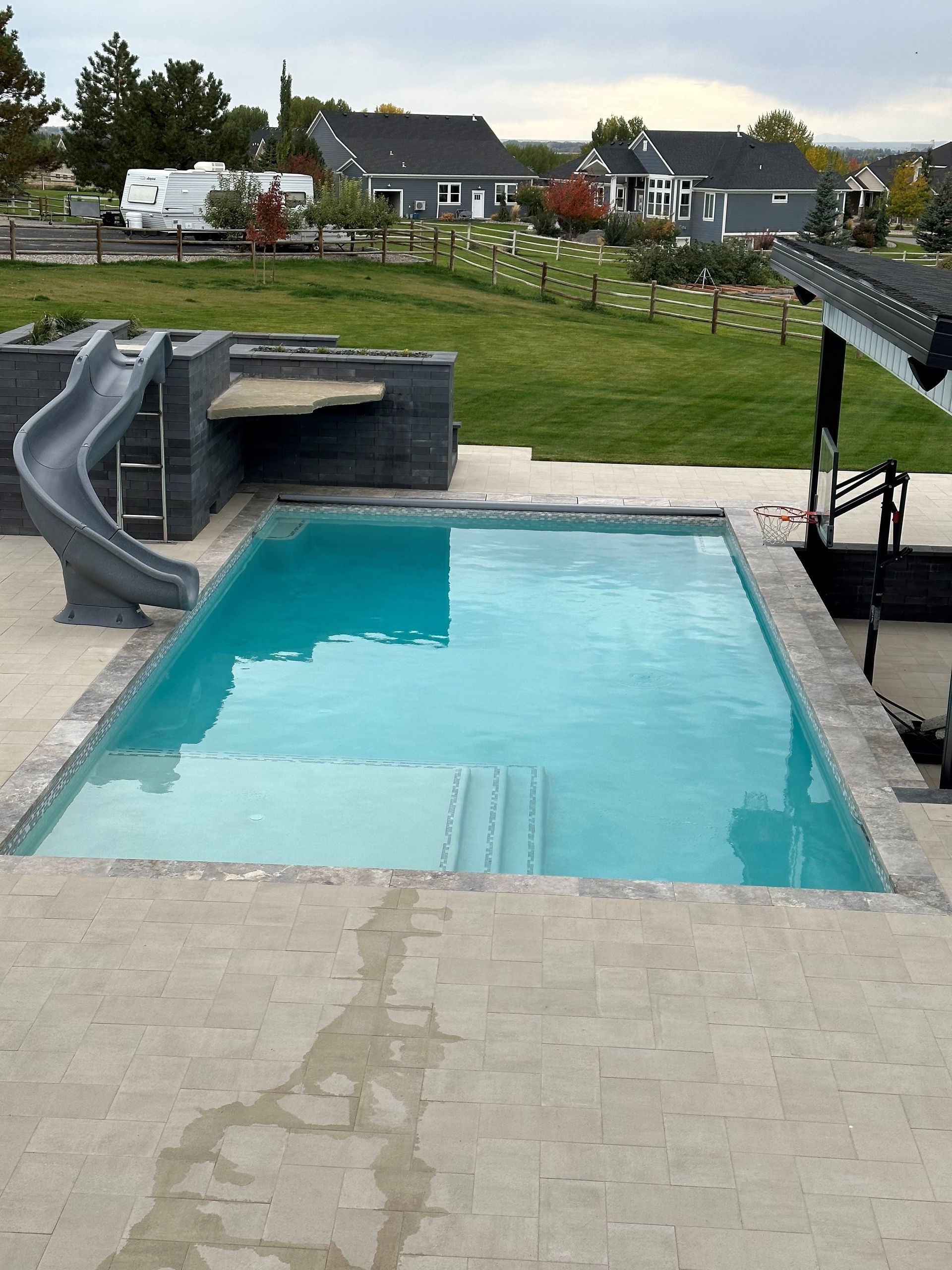 A large swimming pool with a slide in the backyard.