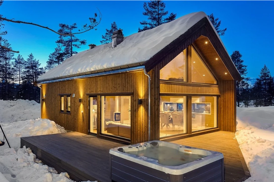 A house with a hot tub in front of it in the snow.