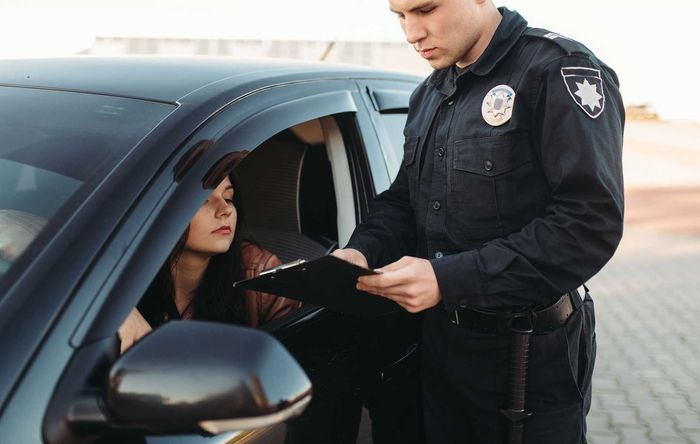 A police officer is talking to a woman in a car. 