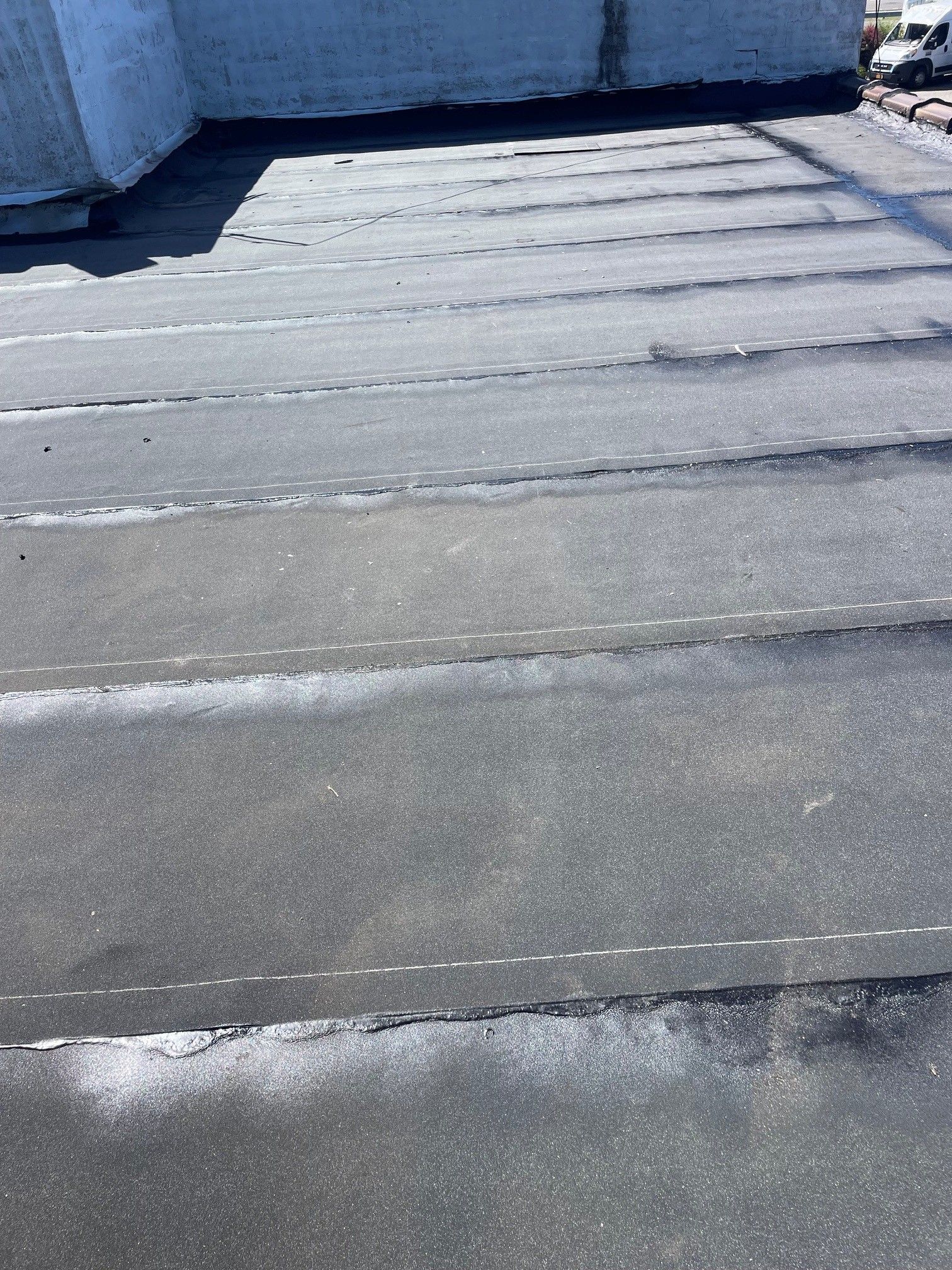 Flat gray rooftop with shallow puddles and a white parapet wall in the background