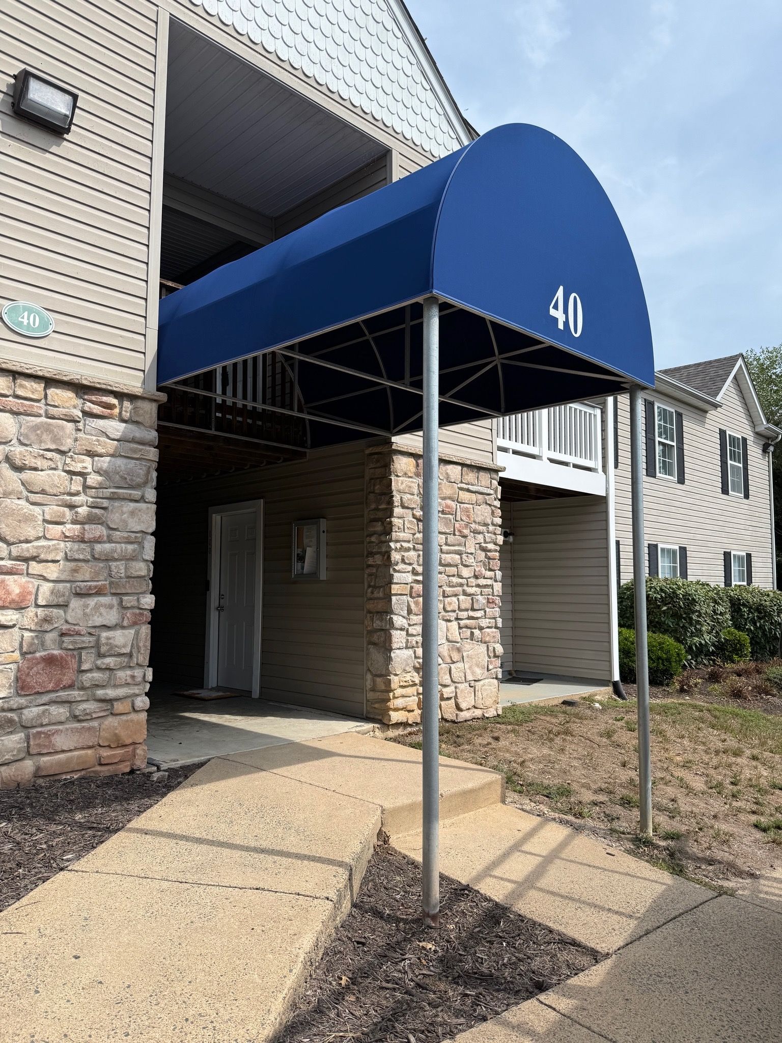 Blue awning over apartment entrance with stone facade and building number 40.