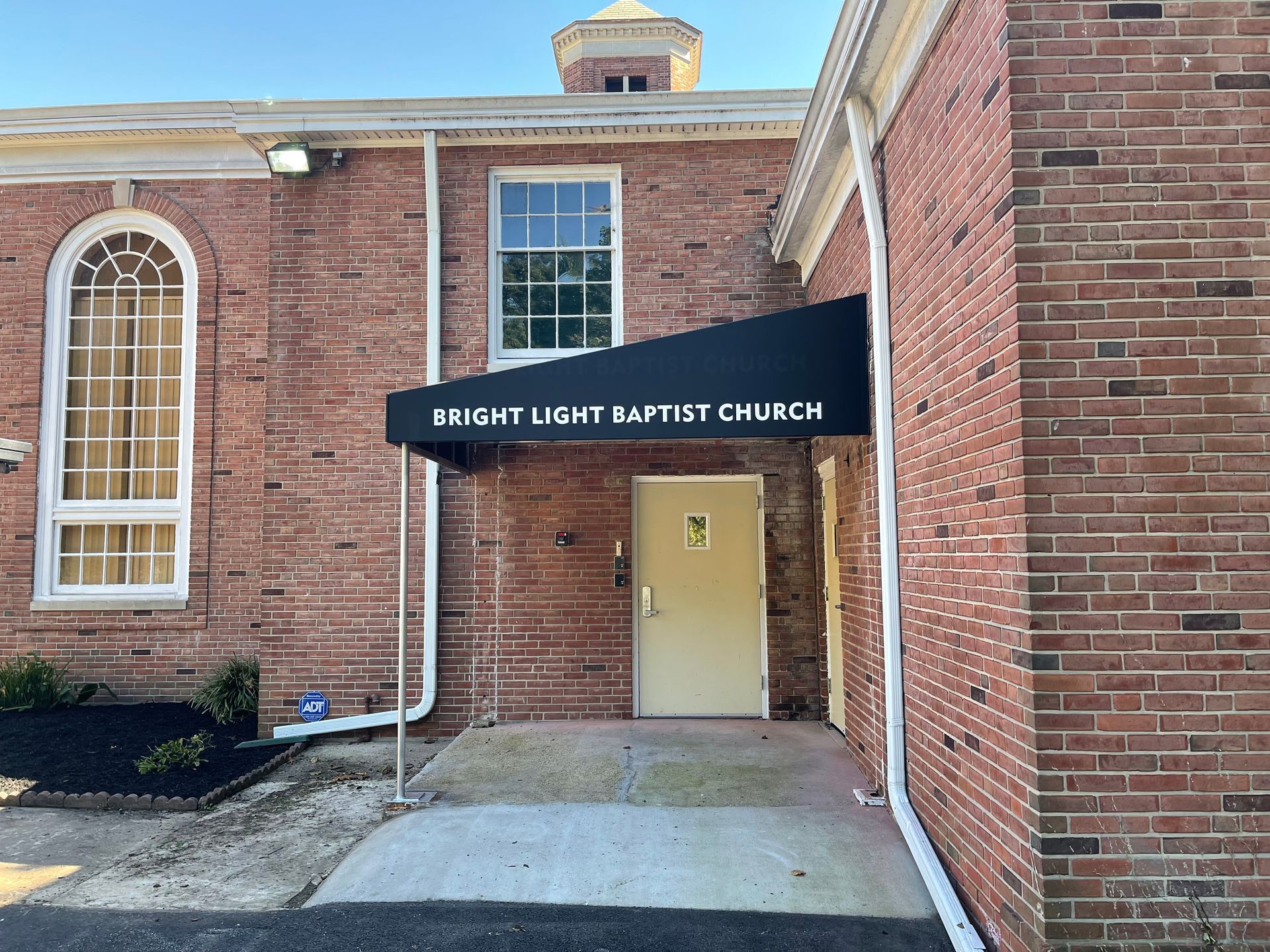 Brick church entrance with black awning reading and an open door