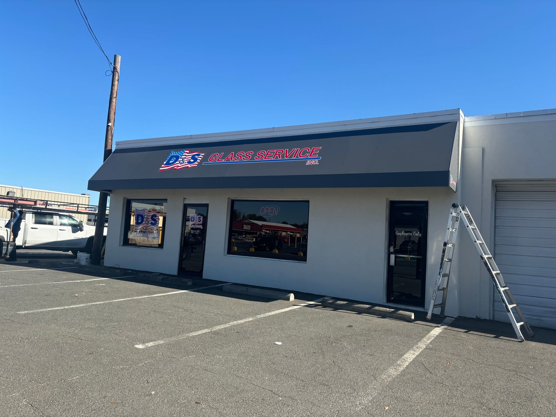 Small roadside storefront with a black awning, gray exterior, and parking spaces in front.